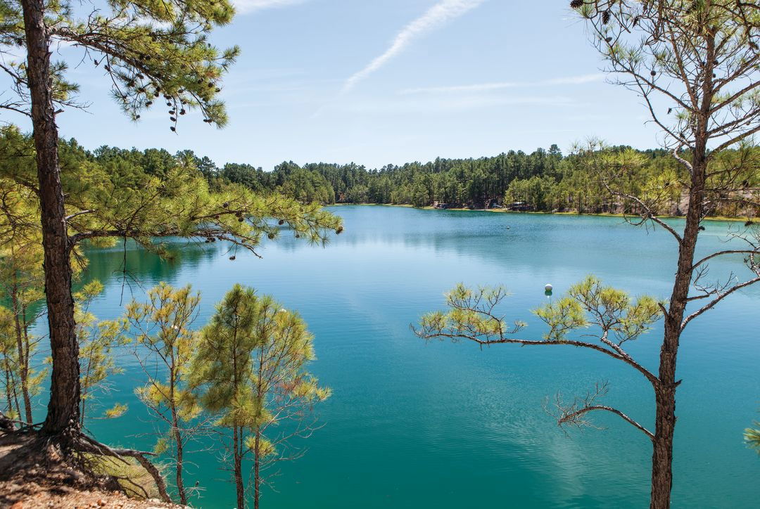 Aquamarine lake surrounded by evergreen trees on the shoreline.