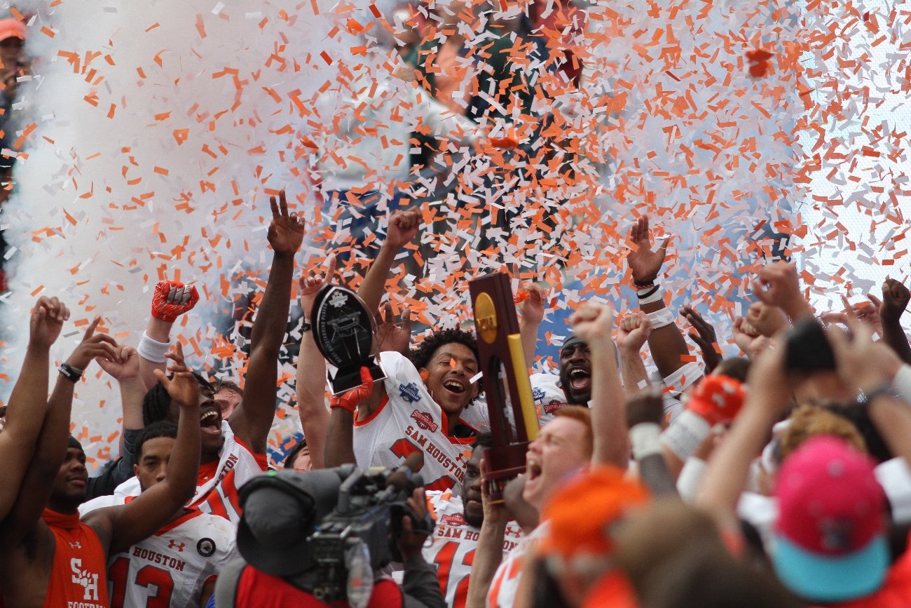 Bearkat football players holding up championship trophy amidst falling confetti.